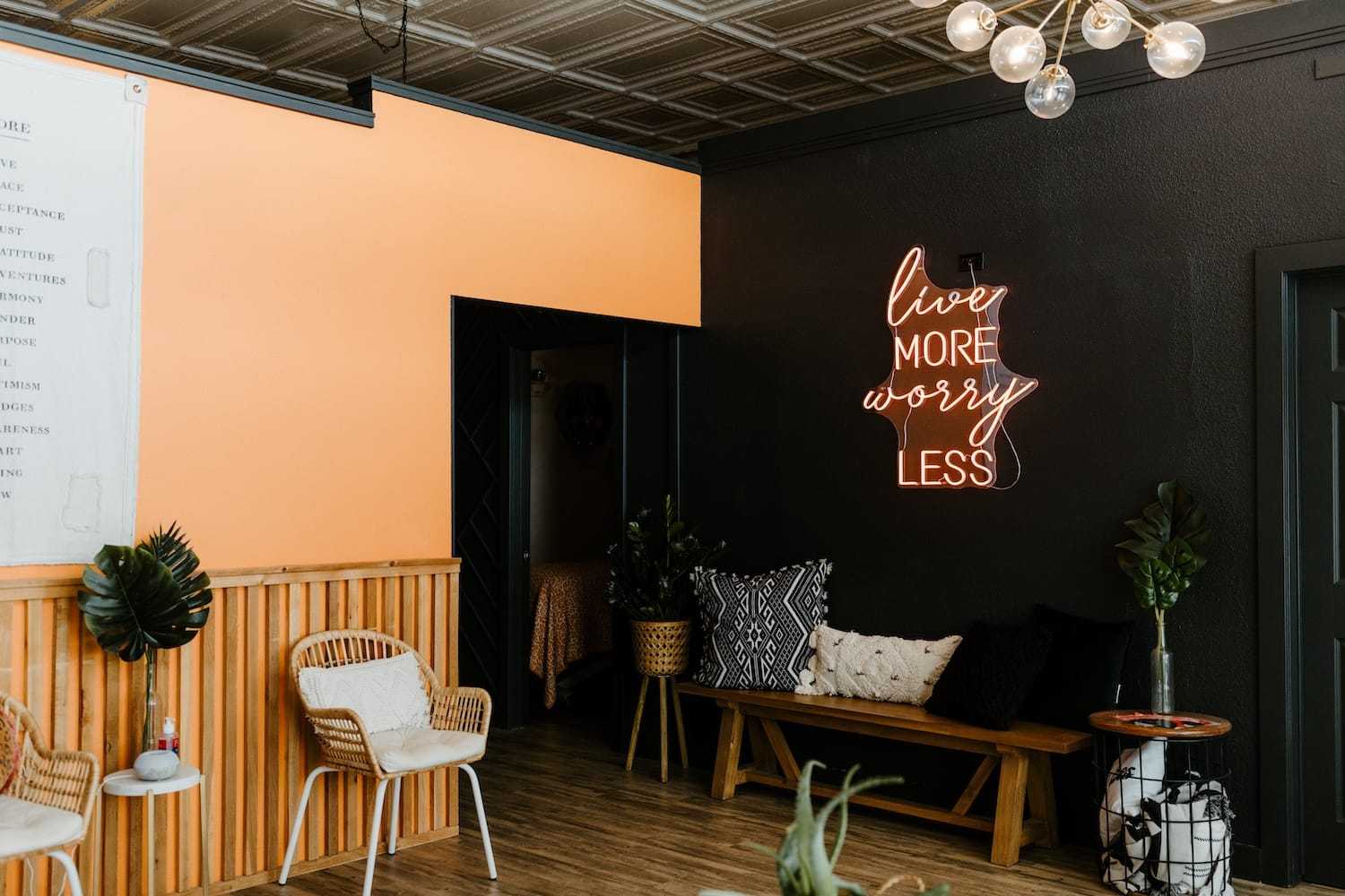 Neon sign on a wall reading 'Live More Worry Less' in a stylish indoor setting.